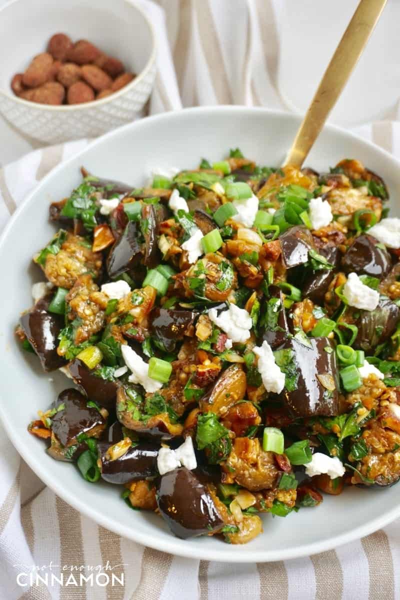 roasted eggplant salad with smoked almonds and goat cheese on a white plate