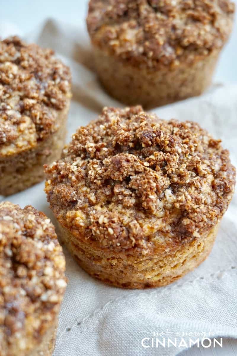 Gluten Free Apple Snickerdoodle Muffins with crumb topping on a white tablecloth