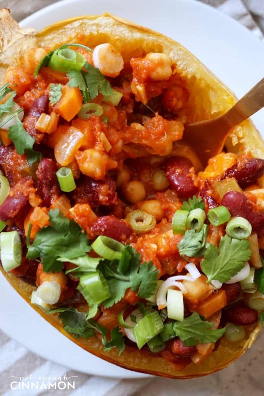 a fork mixing the insides of a Spaghetti squash boat stuffed with vegan chili 