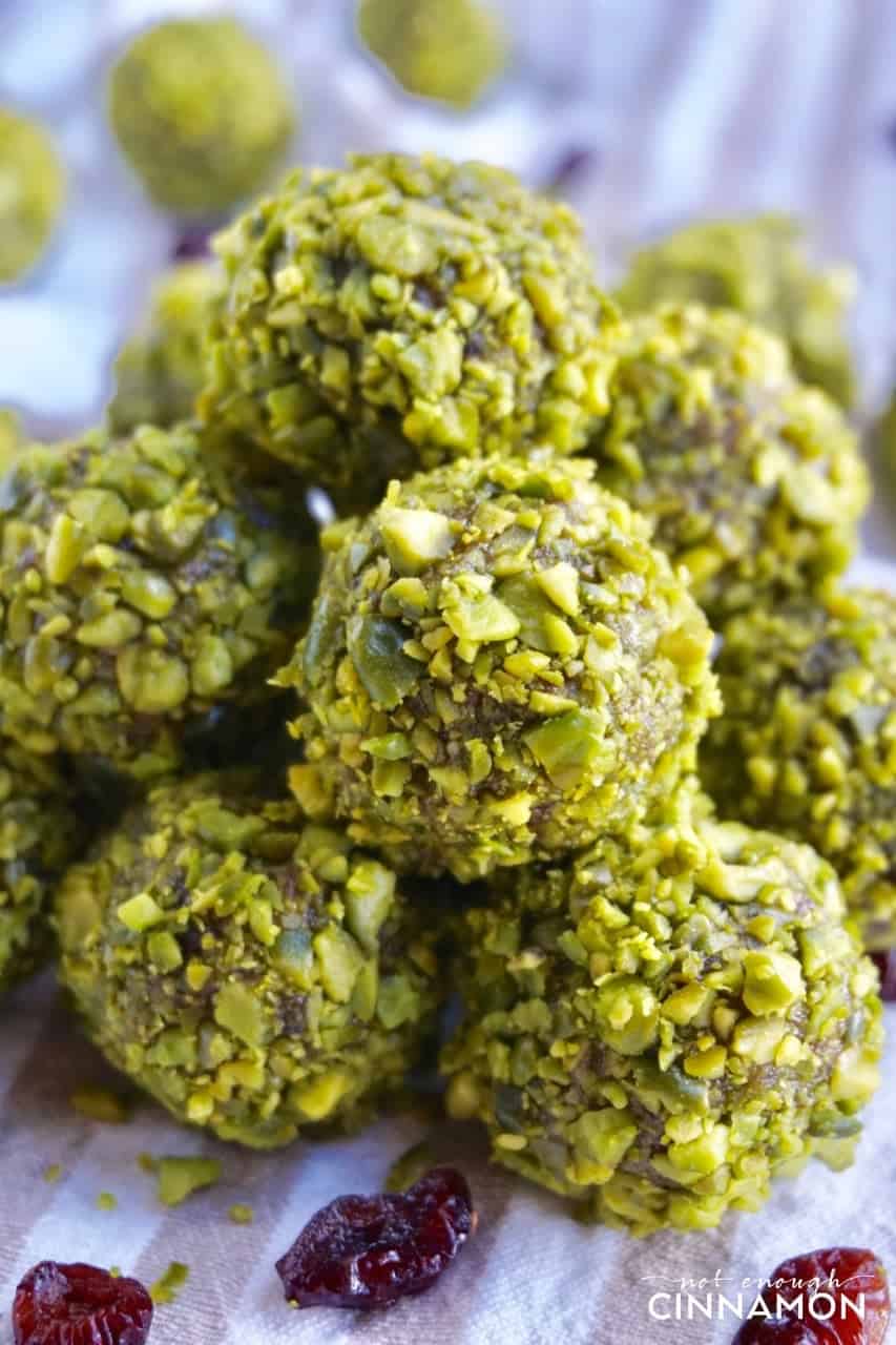  a small pile of paleo energy balls with cranberries and coated with chopped pistachios