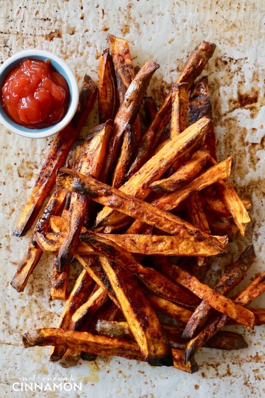 cinnamon-spiced baked sweet potato fries with coconut sugar piled up on parchment paper 