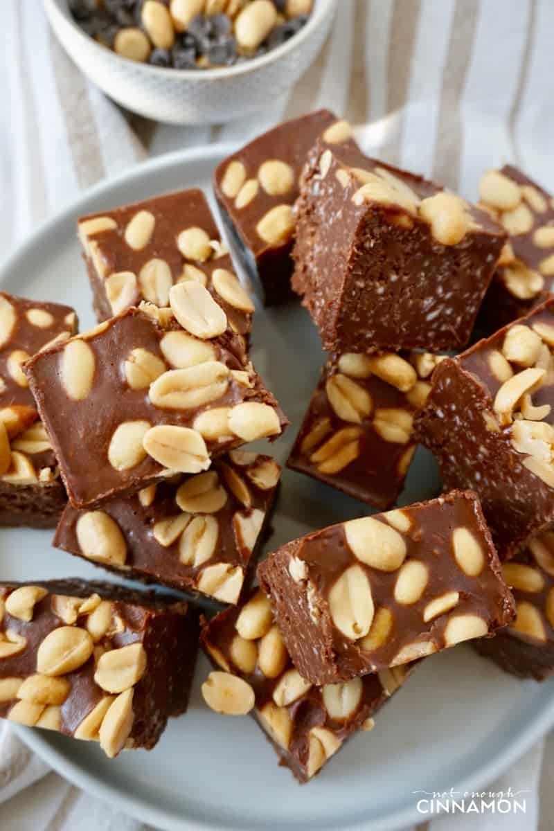 a white plate with healthy peanut butter chocolate fudge cubes topped with peanuts
