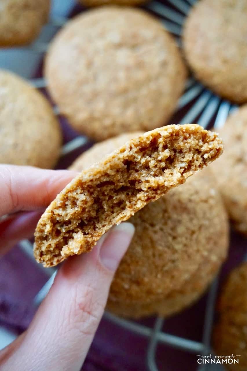 a hand holding a Gluten Free Chai Cookies with more cookies on a cooling rack in the background