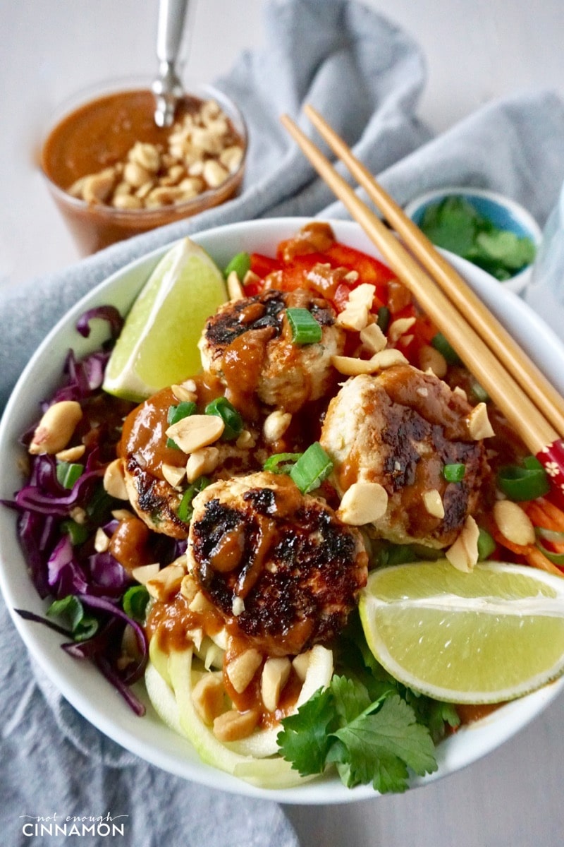 A Thai veggie bowl with spiralized veggies and mini Thai chicken patties drizzled with peanut sauce