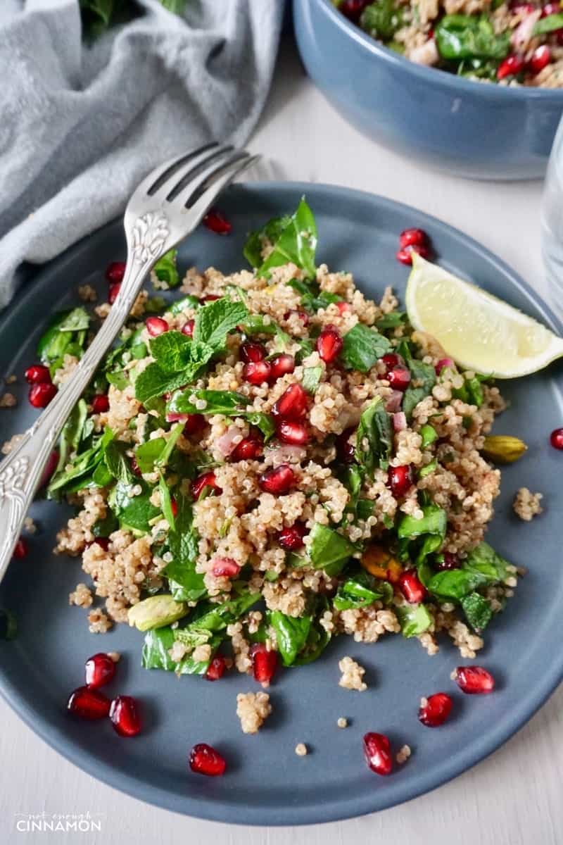 close-up of a plate of vegan quinoa salad with spinach, mint, pistachios and pomegranate arils