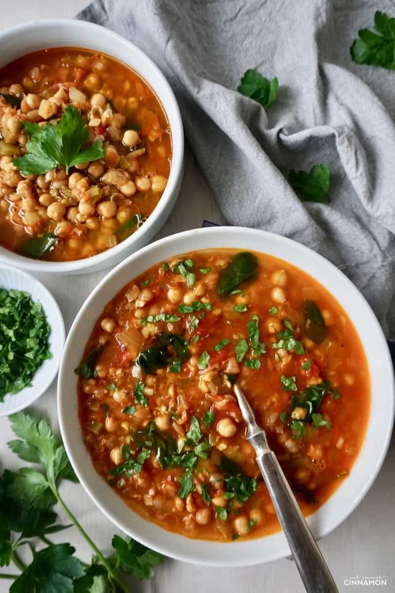two bowls of Moroccan chickpea soup spiced with cumin, paprika and cinnamon on a grey tablecloth