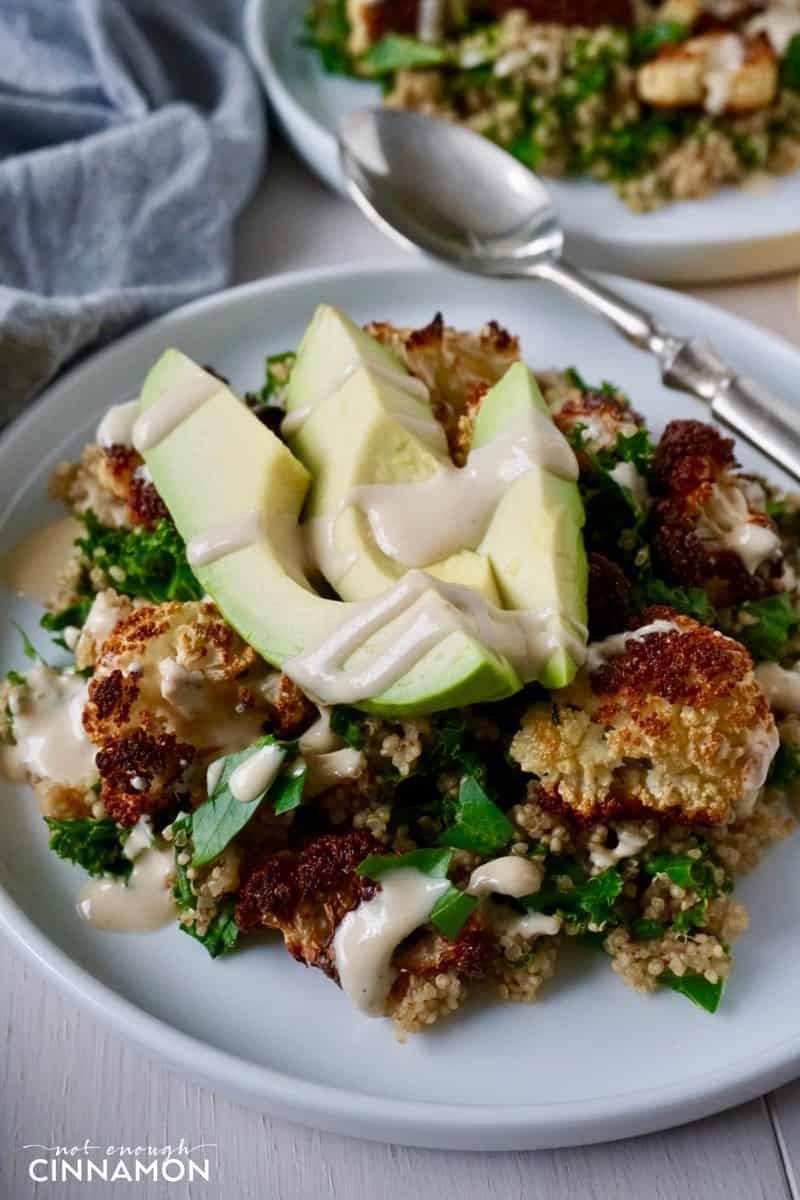 close-up of a plate of quinoa, oven roasted cauliflower and avocado slices topped with tahini sauce