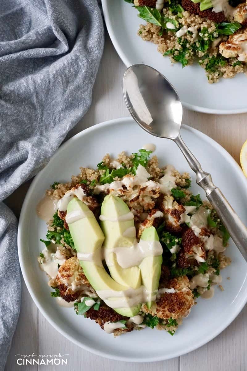 a plate loaded with quinoa, kale and oven-roasted cauliflower drizzled with tahini sauce