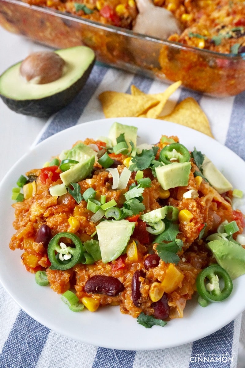 a serving of healthy Mexican quinoa casserole on a white plate topped with cilantro and avocado cubes
