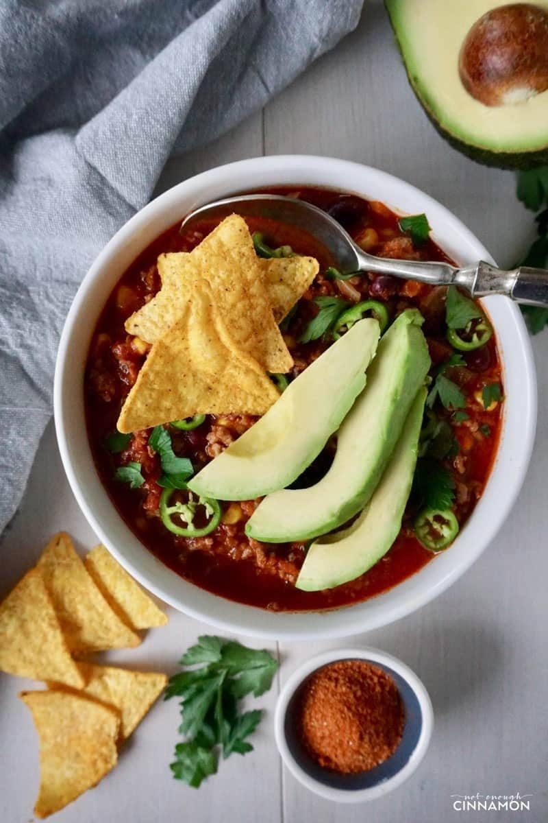 overhead shot of healthy turkey taco soup with nacho chips and avocado slices on top