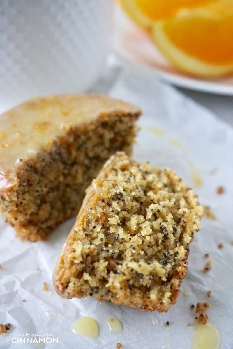 half a gluten-free orange poppy seed muffin with vanilla glaze on a piece of parchment paper