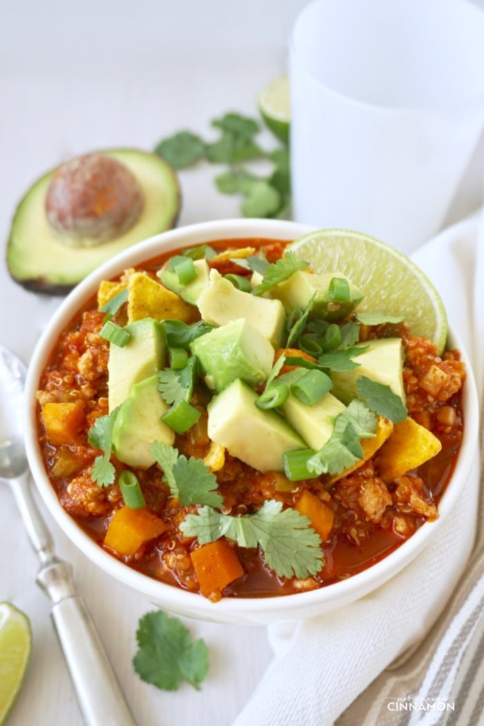a bowl of turkey, chili and sweet potato chili topped with avocado cubes and cilantro
