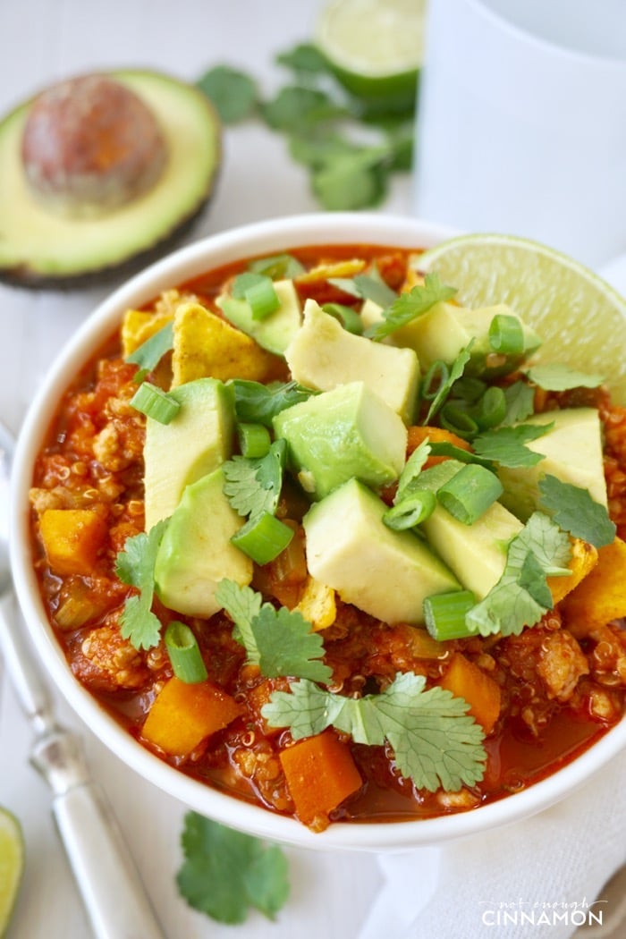 close-up of a bowl if quinoa turkey sweet potato chili topped with avocado cubes and cilantro