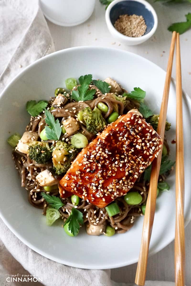 maple glazed salmon fillet on soba noodles, broccoli and edamame beans in a white bowl