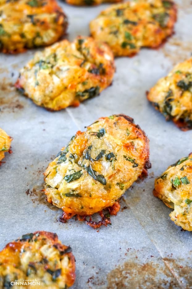 baked zucchini tots on a parchment lined baking sheet