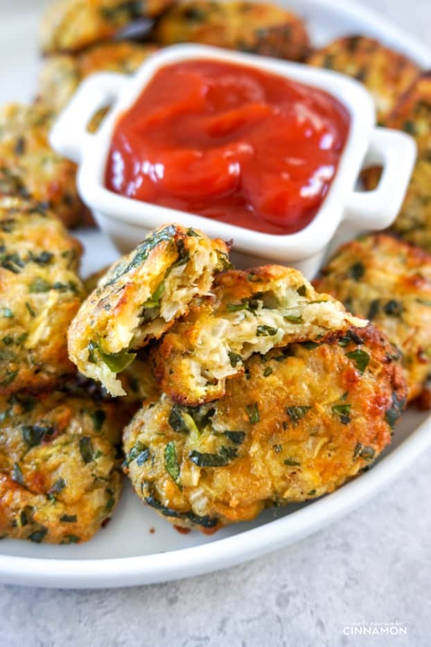 Zucchini tot cut in half on a plate of other zucchini tots with ketchup