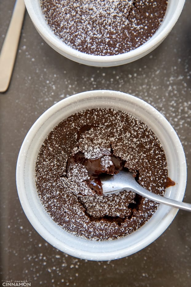 overhead shot of a small ramekin with molten chocolate lava cake with a spoon digging into the molten center