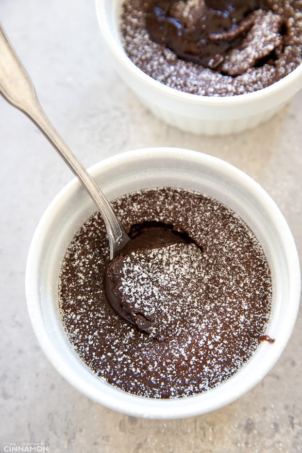 a spoon digging into the center of a healthy gluten-free paleo chocolate lava cake in a small white ramekin