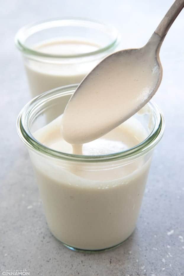 a small glass of homemade vegan cashew cream with a silver spoon