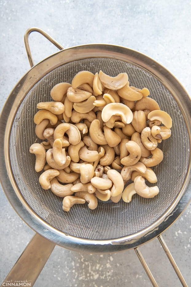 soaked cashew nuts being drained in a sieve 