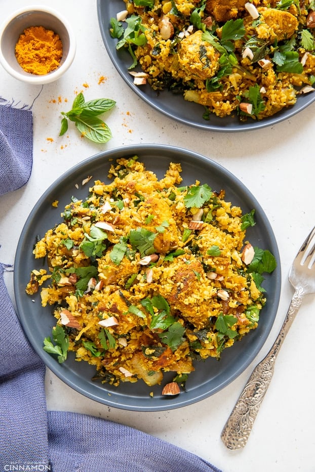 overhead shot of two plates with paleo chicken biryani cauliflower rice stir fry topped with chopped herbs