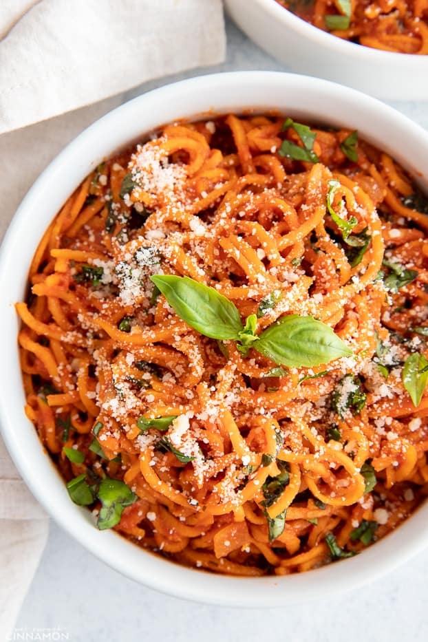 overhead shot of an Italian sweet potato noodle bowl with parmesan cheese and fresh basil 