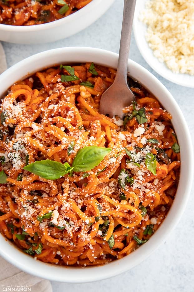 overhead shot of a bowl of sweet potato pasta tossed with tomato sauce sprinkled with parmesan cheese