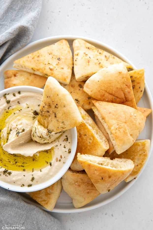 overhead shot of a bowl of homemade baked Stacey's Pita Chips with a small bowl of hummus