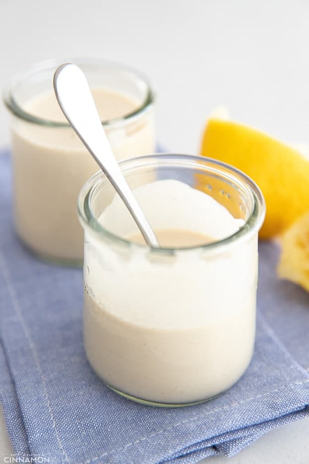 side view of a jar of homemade Tahini sauce with a spoon