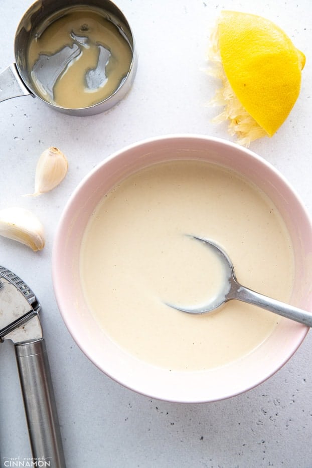 tahini sauce being stirred together in a white bowl