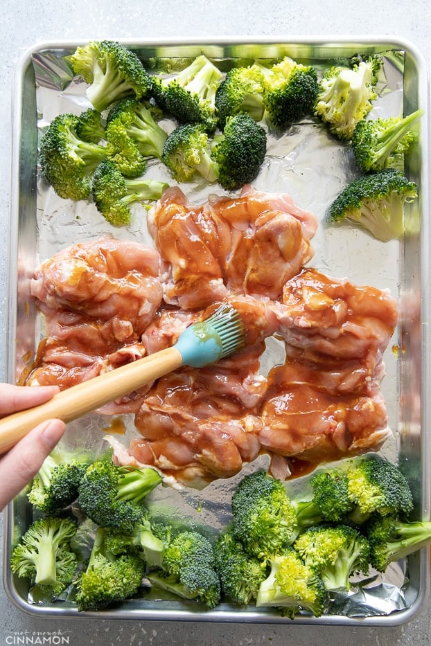 chicken thighs being brushed with Whole30 teriyaki sauce to make sheet pan chicken dinner