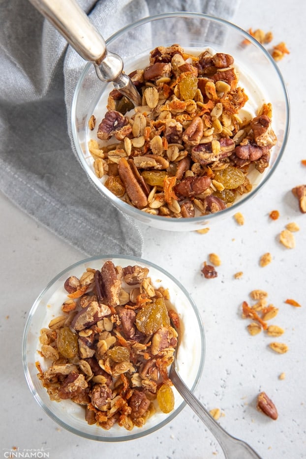 overhead shot of two dessert glasses layered with vegan carrot cake granola and yogurt