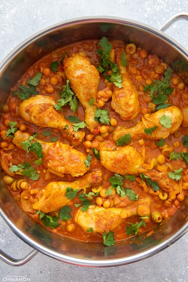 overhead shot of a pot filled with Moroccan chicken drumsticks simmered with chickpeas, raisins and lemon