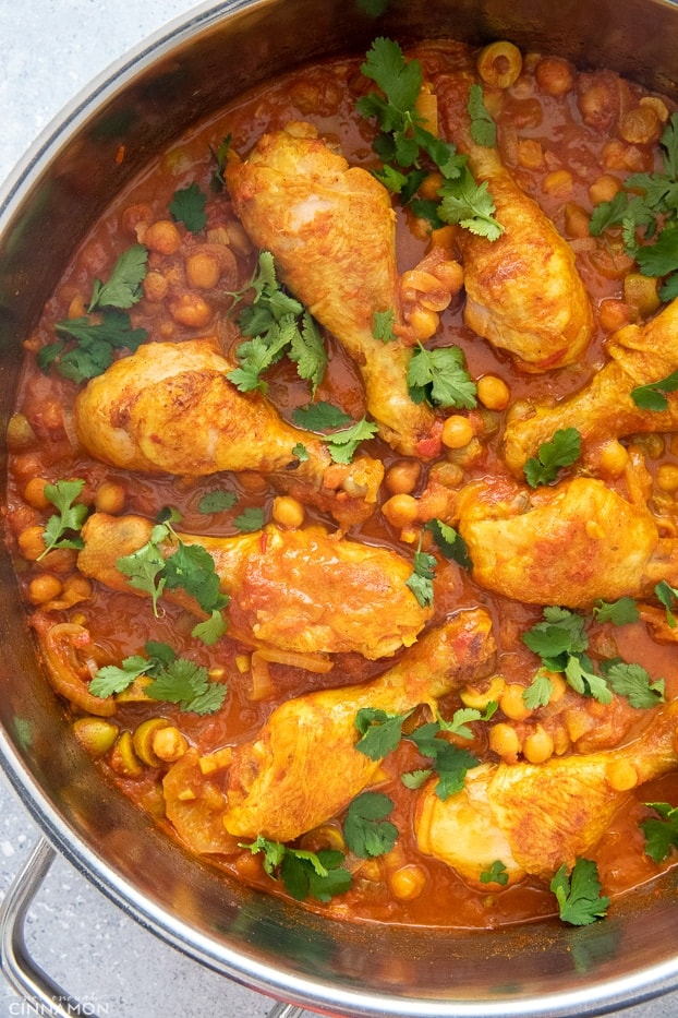 overhead shot of a pot of Moroccan chicken stew simmering with dried fruit, chickpeas and olives