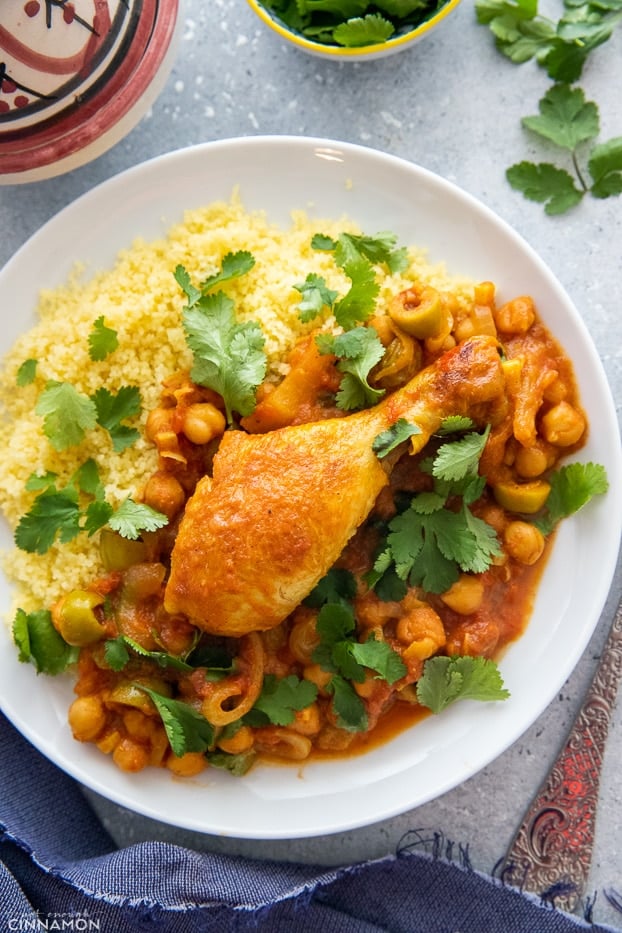 overhead shot of a serving of Moroccan chicken tagine served with a side of fluffy couscous and chickpeas