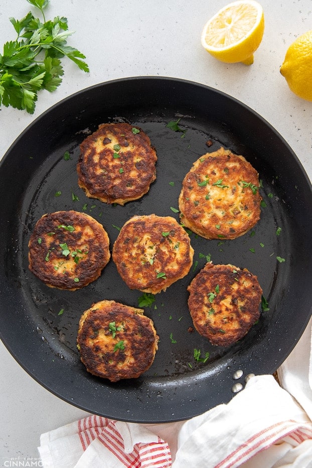 overhead shot of a black skillet with salmon patties frying in it