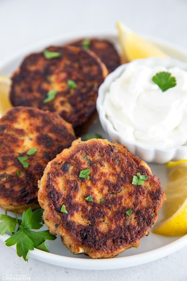 three healthy salmon patties with sour cream dip on the side