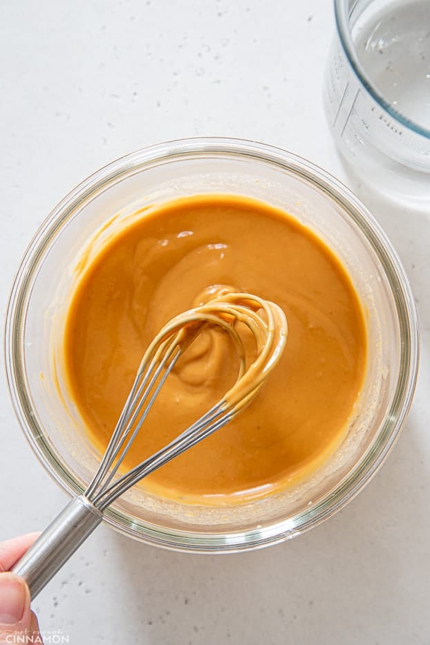 creamy dairy-free Thai peanut dressing being stirred in a glass bowl 