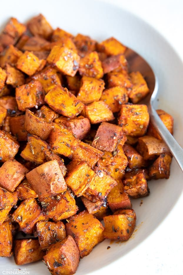 side view of oven perfect cubes of roasted sweet potatoes served in a white bowl 