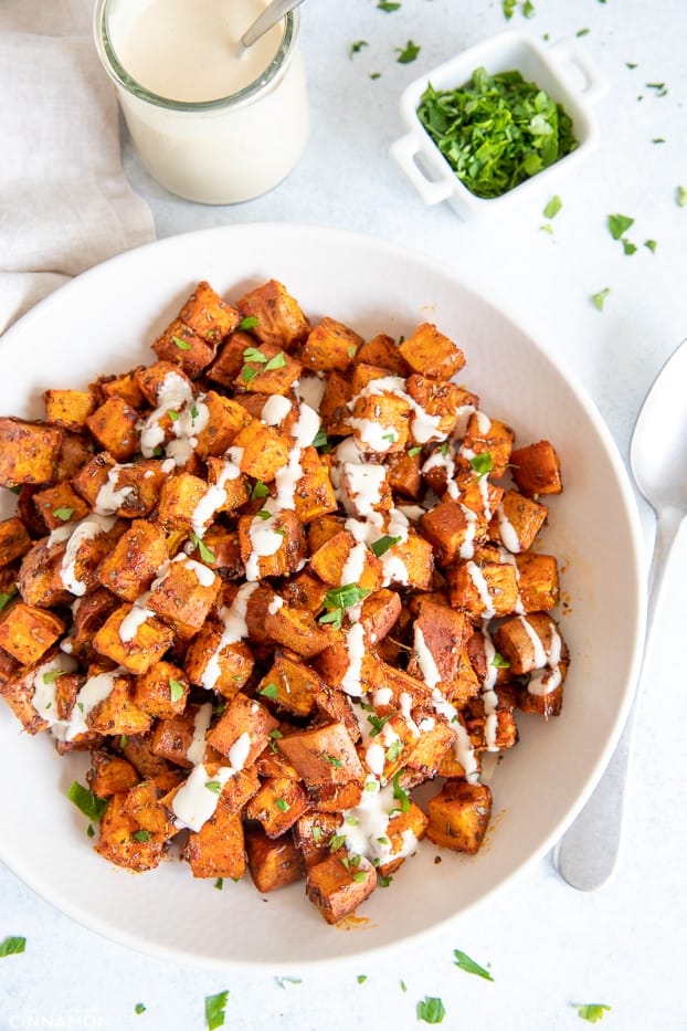 overhead shot of the best roasted sweet potatoes drizzled with white alfredo sauce