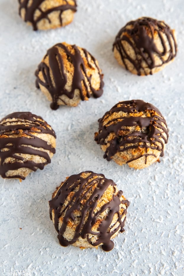 overhead shot of chocolate-drizzled paleo coconut macaroons surrounded with shredded coconut 