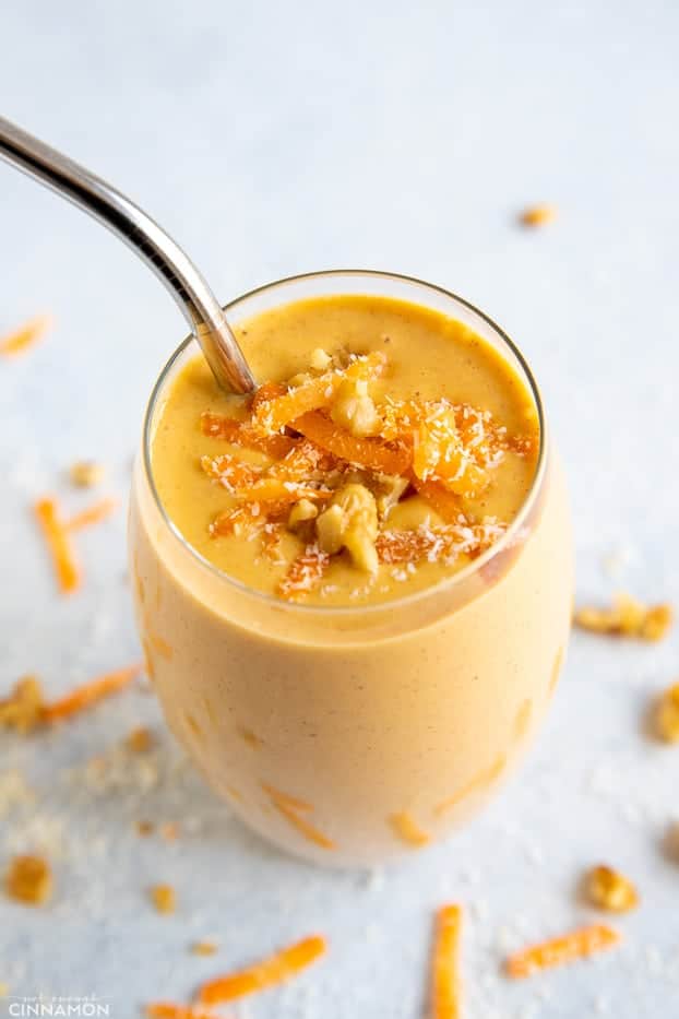 overhead shot of a tall glass with carrot cake smoothie topped with coconut and grated carrots