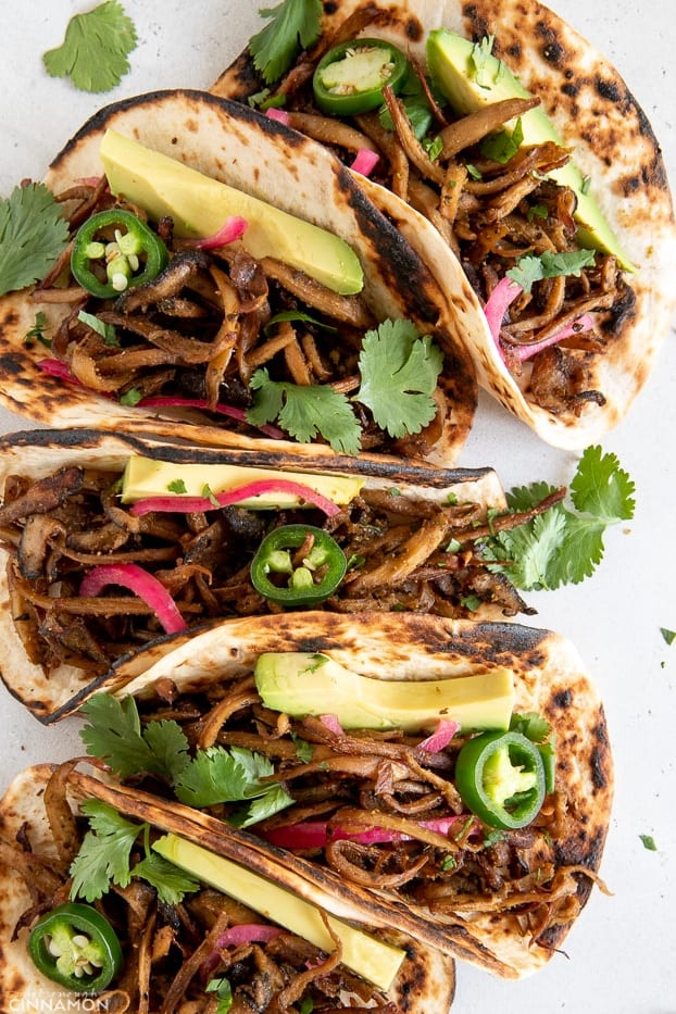 overhead shot of vegan mushroom carnitas tacos topped with avocado and cilantro