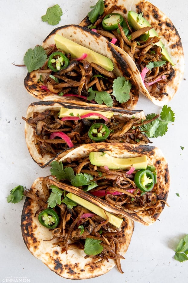 overhead shot of vegan mushroom carnitas tacos topped with Jalapeno and cilantro leaves 