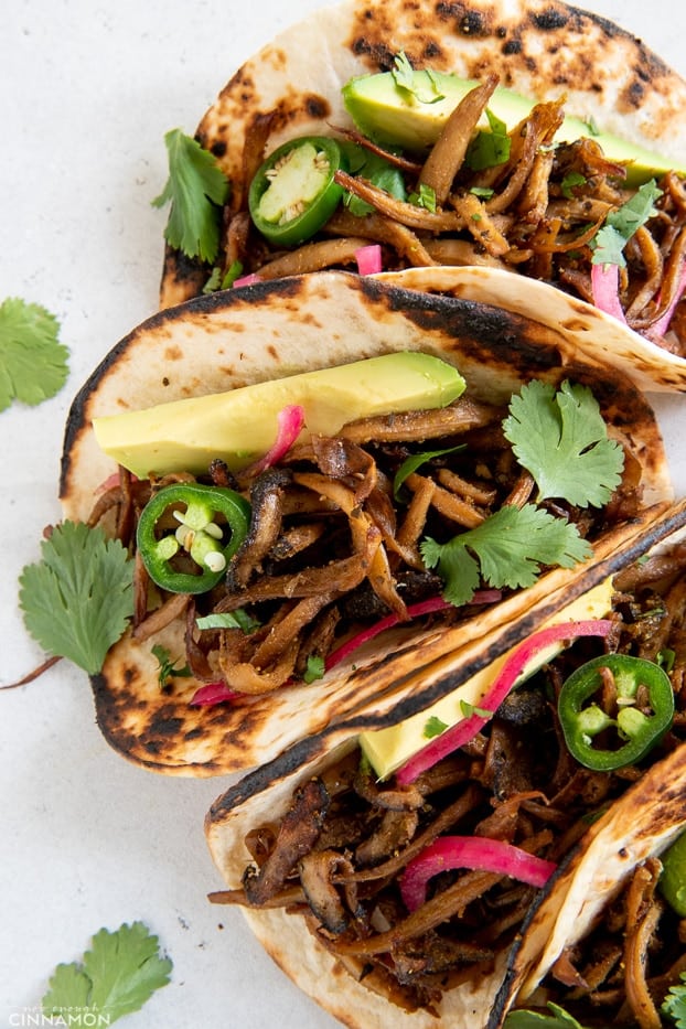 overhead shot of vegan mushroom carnitas tacos tipped with cilantro, quick pickled onions and avocado 