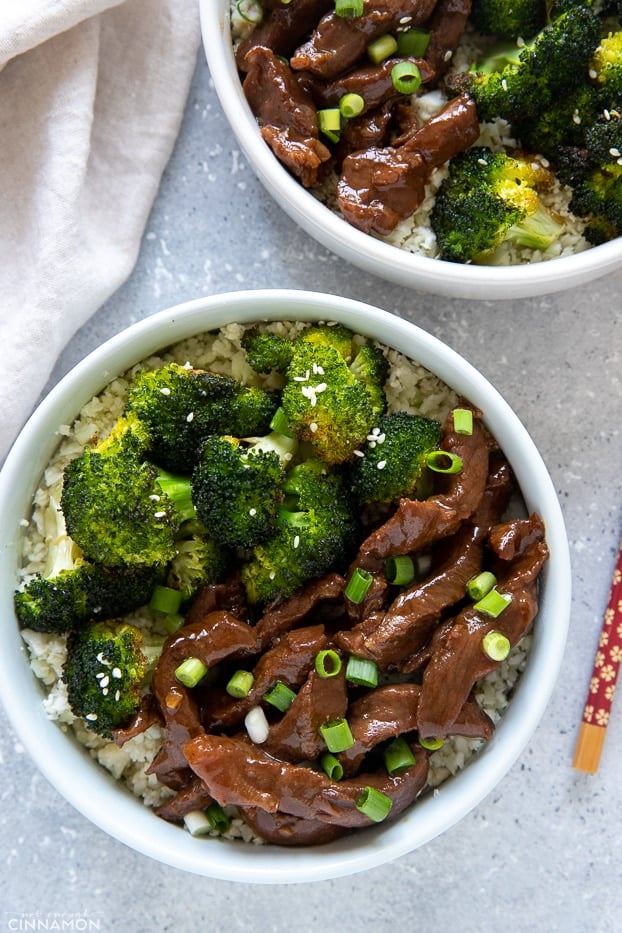 two bowls of paleo pf changs slow cooker Mongolian Beef and Broccoli served on cauliflower rice 