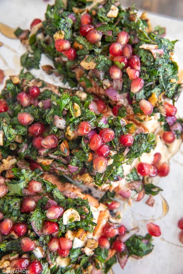 overhead shot of parchment paper baked salmon fillets served with an herb topping and pomegranate seeds