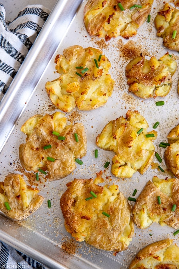 overhead shot of a baking sheet with baked smashed potatoes with crispy edges