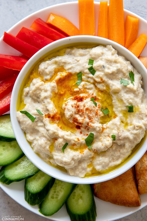 a bowl of homemade healthy baba ganoush surrounded with veggie sticks 