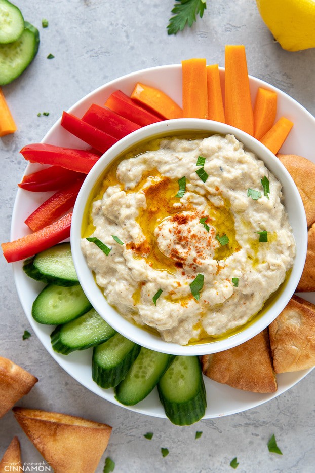 overhead shot of a serving of baba ganoush served in a small bowl surrounded with veggies